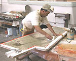 An employee applies fiberglass to a rudder mold.